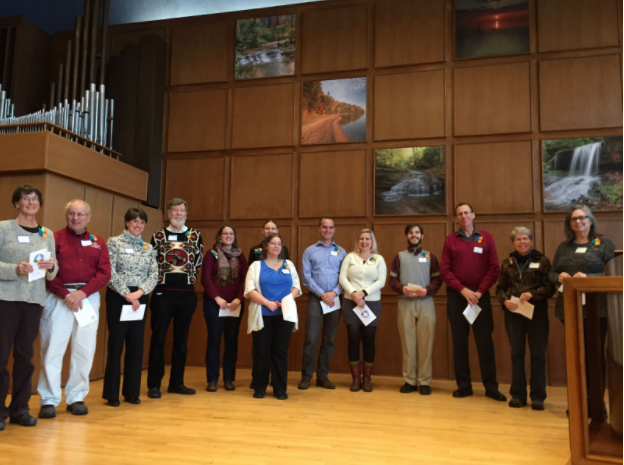 Group of thirteen individuals standing on the FUS stage during a New Member Sunday.